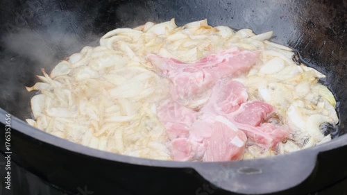 chopped onions and meat are fried in oil in a cauldron