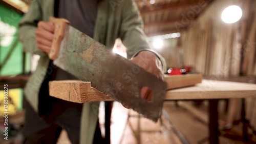 A man is holding a saw and cutting a piece of wood
