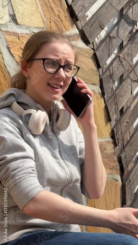 A young woman is talking on the phone while sitting on a bench. 