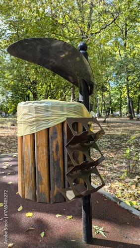 Modern outdoor trash bin with bottle recycling holder – wooden and metal litter container in city park during autumn season