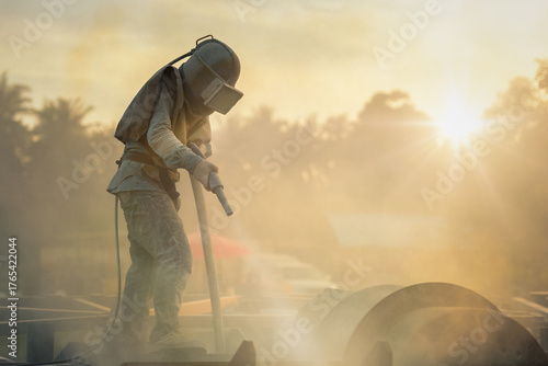 Sand blasting process, Industial worker using sand blasting process preparation cleaning surface on steel before painting in factory workshop.