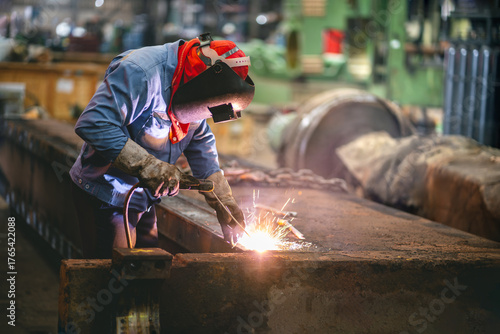 Industrial welder welding repait heavy construction in factory, Welding process by Shielded Metal Arc Welding (SMAW) or Stick Welding.