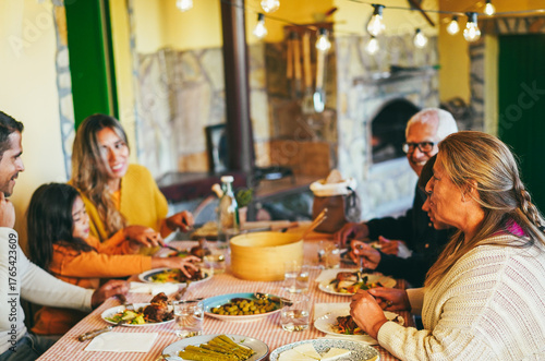 Happy latin family cheering and eating dinner together at home - Winter holidays and Christmas time concept - Main focus on grandmother head