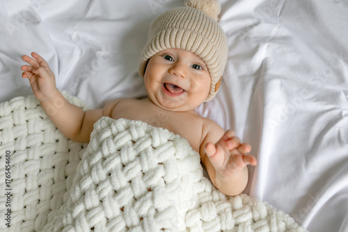 Adorable newborn baby smiling top view. wearing knitted hat