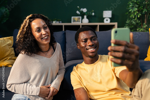 Happy diverse couple taking selfie with smartphone at home