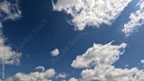 Fast flowing to the right side bright clouds in the blue skies. 4K video (Ultra High Definition) of cloudscape and bright sun. Sun shines through clouds on the blue sky background.
