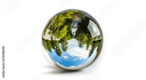 Clear crystal ball reflecting an inverted green forest and blue sky, showcasing optical distortion.