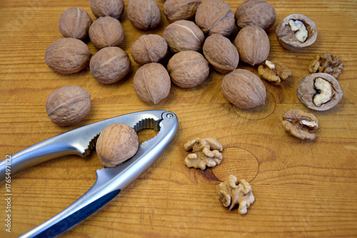 Walnuts and nutcracker on wooden pine board. Close-up. Copy space. Selective focus.
