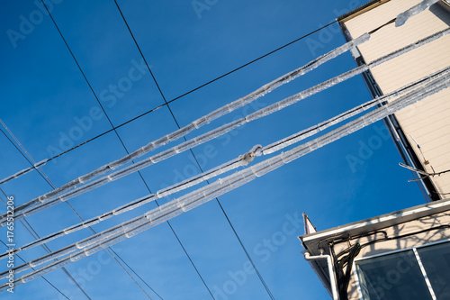 Icicles hanging from power lines against a clear blue sky.