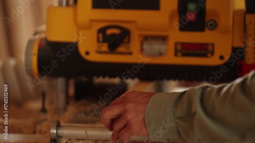 A person is using a woodworking tool with a yellow handle