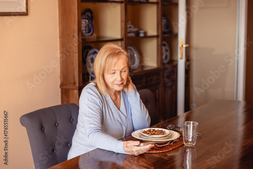 Elderly woman using phone while eating dinner in solitude, independence concept