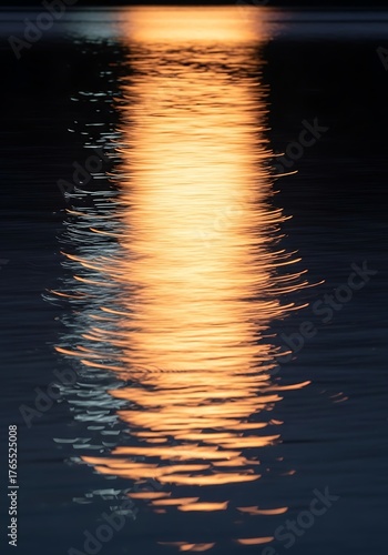 Mesmerizing golden shimmer reflection on dark rippled water surface