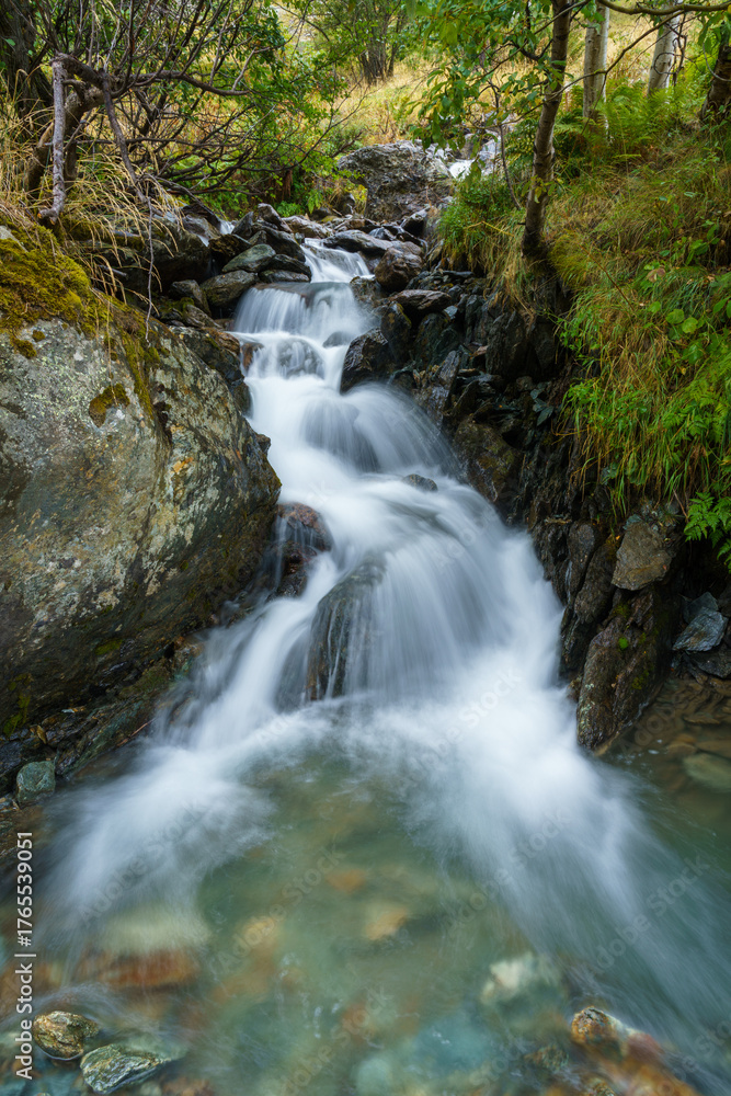 Fototapeta premium Gentle waterfall cascades over mossy rocks