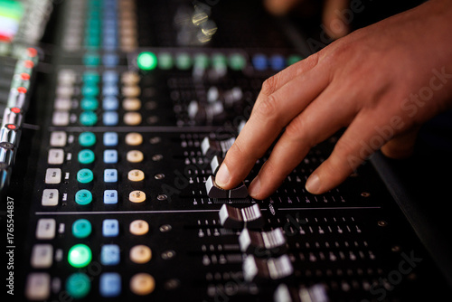 Fototapeta Hand adjusting audio mixer faders during event
