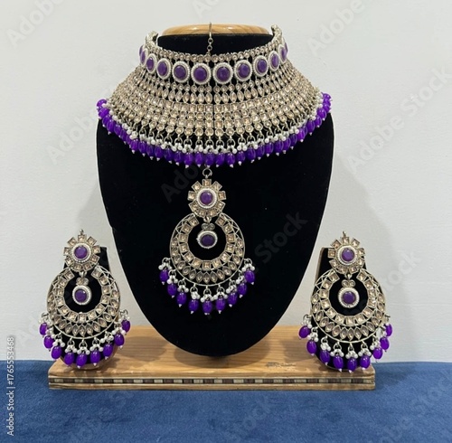 Indian jewelry set featuring a silver-plated choker necklace, matching earrings, and a maang tikka. The set is adorned with purple stones and beads, giving it a traditional yet elegant look. It is ide
