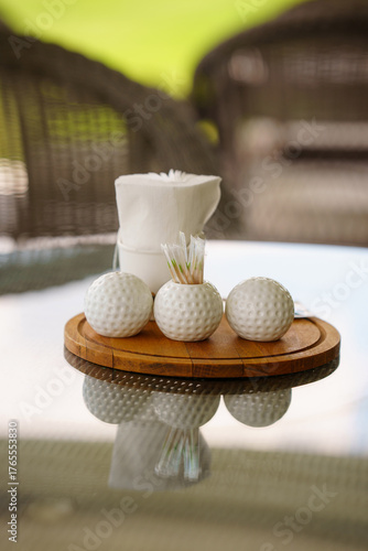 Golf accessories on a wooden tray at a sunny patio