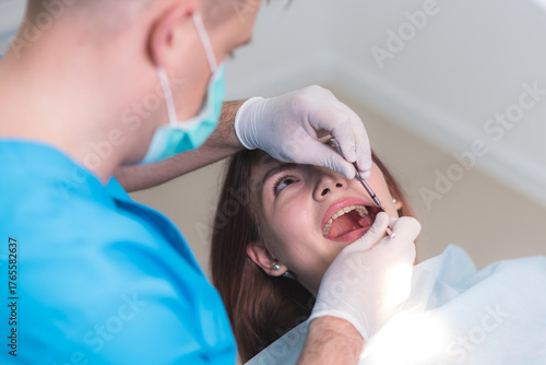 doctor orthodontist examines the oral cavity of a beautiful patient