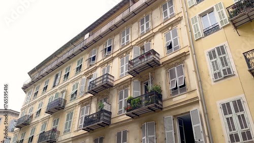 Bottom view of old, traditional buildings in famous touristic city called Nice located in French riviera. It shows French architectural style.