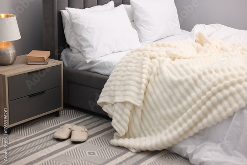 Tableau sur toile Large bed with linens, nightstand and slippers near grey wall in bedroom