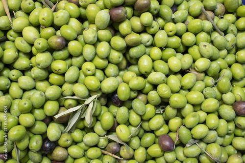 Fresh green olives with leaves filling the frame, natural pattern and overhead composition; for food design, retail signage, agriculture content, education.