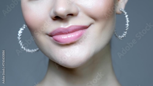 Closeup macro video of female lower part of face. Woman with earrings in ears.