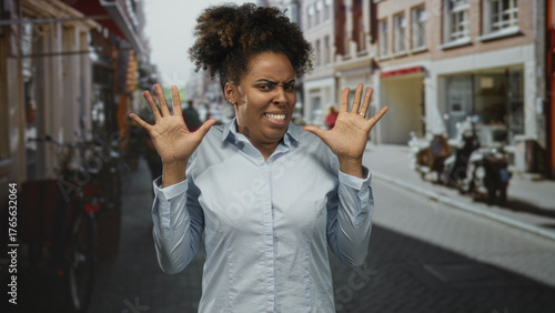 Woman with hands raised and grimacing on a street, palms splayed in a defensive gesture against a busy city lane; disgust avoidance.