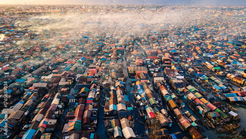 Aerial view of a sprawling settlement, where colorful rooftops nestle tightly together, intersected by waterways filled with boats, creating a vibrant tapestry of life, Lagos, Lagos, Nigeria.