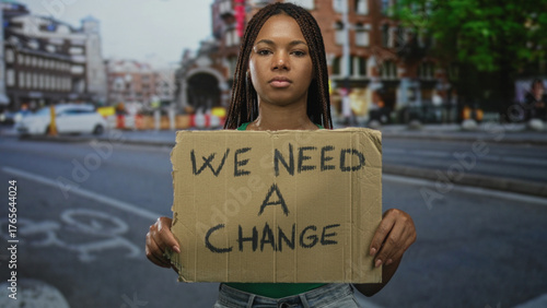 Wallpaper Mural Woman holding cardboard protest sign on street wearing green shirt and braids; social change determination. Torontodigital.ca