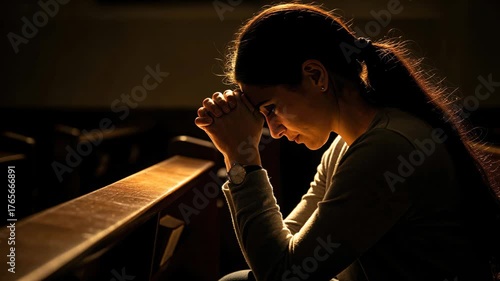 Christian woman praying alone on his knees in church with warm light representing faith and hope.