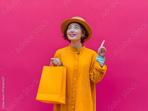 woman holding paper shopping bag and pointing upward