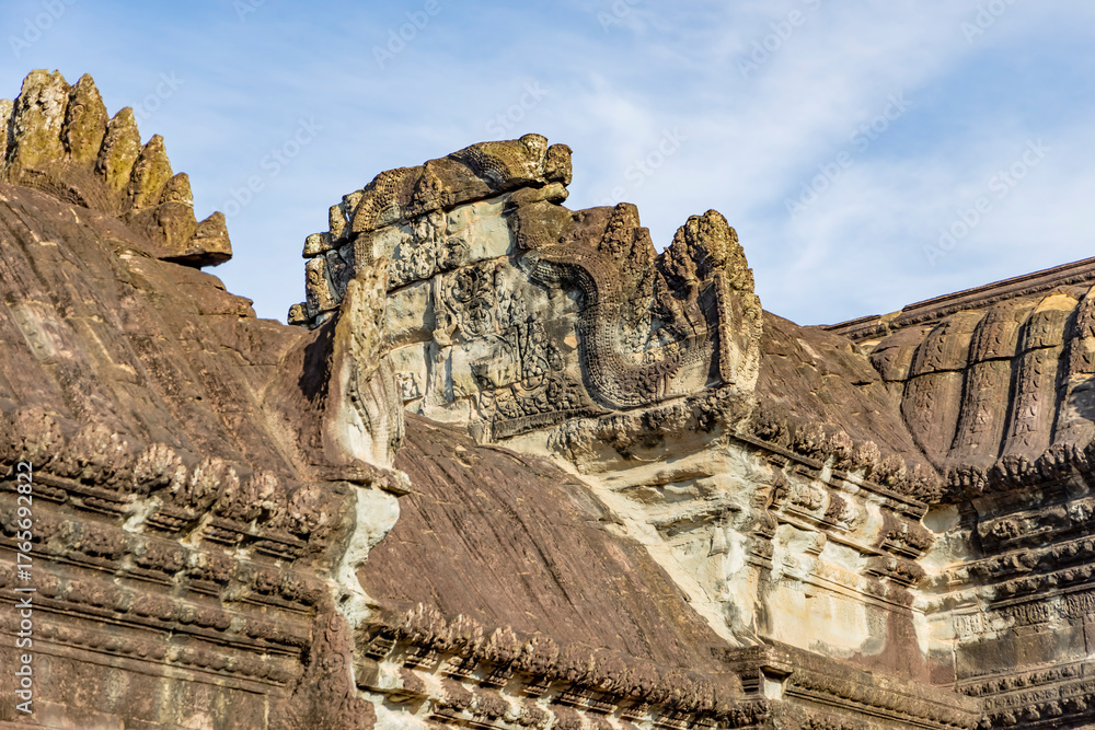 Obraz premium Close-up of ancient roof pediment carvings with naga on angkor wat temple in siem reap, cambodia, showing weathered sandstone detail in warm morning light