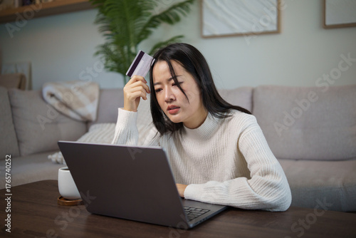 Young woman frustrated while shopping online or facing banking issue at home using laptop.