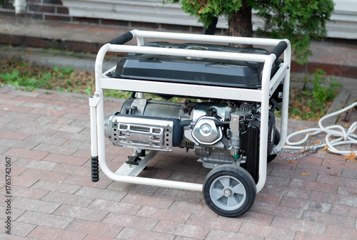 Portable gasoline or diesel power generator with a white frame and wheels standing on a brick patio outdoors.