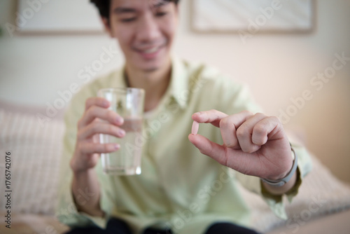 Man preparing to take a vitamin supplement with water. Concept of daily health routine, nutrition, and self care lifestyle.