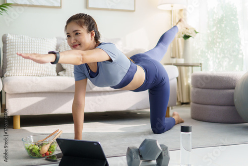 Woman in sportswear maintaining balance pose during home exercise. Concept of healthy lifestyle, and home fitness.