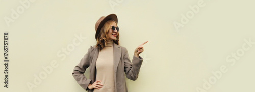 Beautiful happy woman pointing her finger to the side looking away on white background, copy space