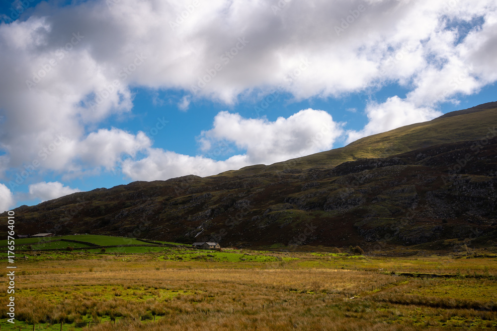 Fototapeta premium Isolated Farmhouse Beneath Dramatic Clouds in Snowdonia Valley, Wales
