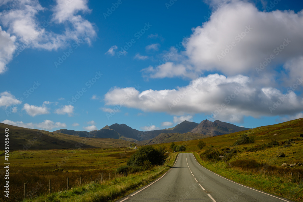 Naklejka premium Lonely road leading toward Mount Snowdon under blue sky, Snowdonia, Wales