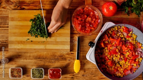 A young woman prepares ingredients for a quesadilla, chopping fresh herbs with a pan of colorful vegetables nearby. Top view of the process of preparing a delicious quesadilla from fresh ingredients.