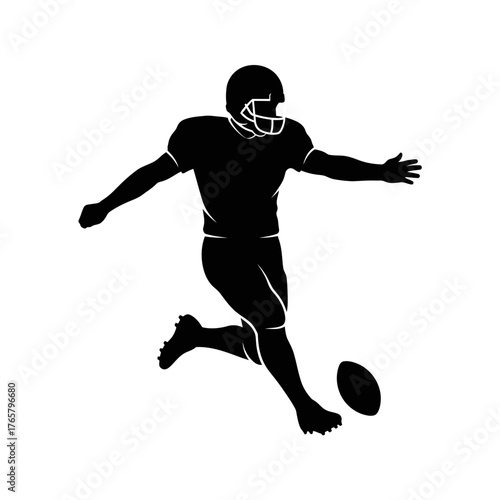 Silhouette of an American football player kicking a football during a game.