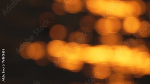blurry yellowish-orange sunset over water. The water appears to be rippling and the sky is filled with a warm, golden glow.