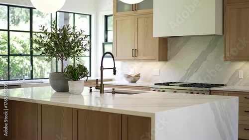 A luxurious modern kitchen with a white quartz waterfall island, light wood cabinets, and large windows showcasing an elegant home interior design
