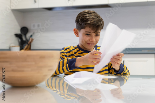 Little boy making paper crafts at home kitchen table