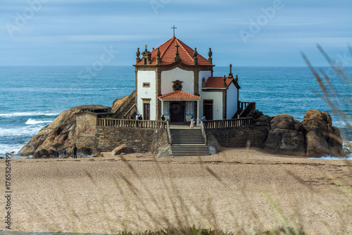 A picturesque white chapel with a red-tiled roof and cross