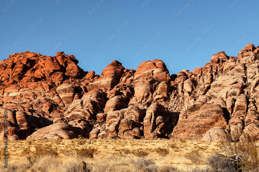 Fototapeta premium Vibrant Red Sandstone Peaks Rise Majestically Against Azure Skies in Red Rock Canyon's Ancient Desert Embrace, Nevada