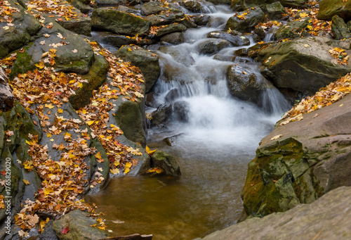 A serene cascade on the Smokey Hollow Falls Trail in Hamilton, Ontario captures the perfect autumn scene with flowing water and colorful leaves.