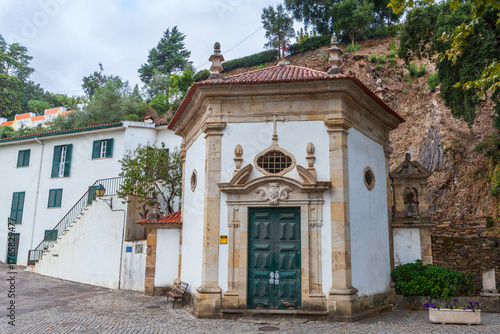 A small, ornate white chapel with a green door and terracotta roof