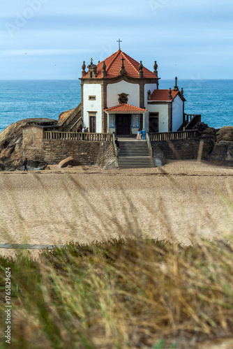A picturesque white chapel with a red-tiled roof and cross
