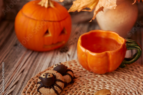 Aesthetics festive Halloween spider cookies with cup of tea in shape of pumpkin. Jack o lantern.