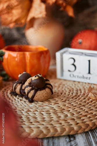 Halloween cookies in shape of spider and cup of tea in shape of pumpkin near 31 of October on calendar